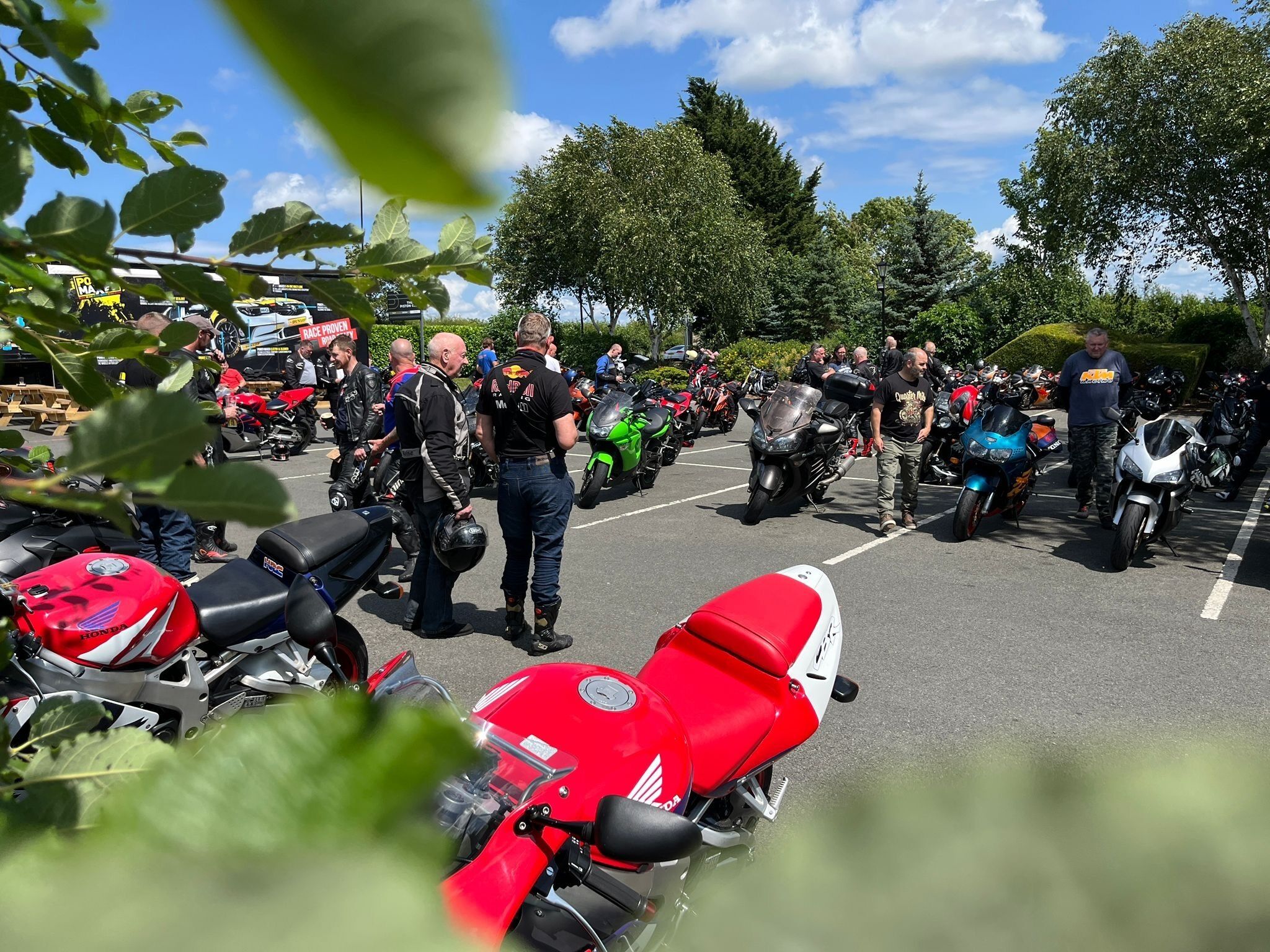 A parking lot with multiple motorcycles and people.