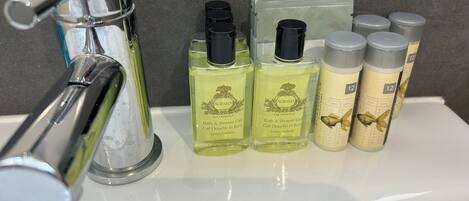 Un lavamanos con un grifo cromado y varias botellas de productos de baño.