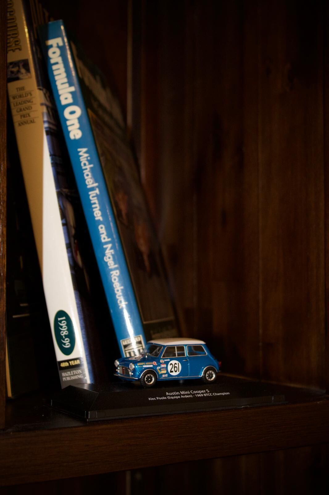 A shelf with books and a model car.