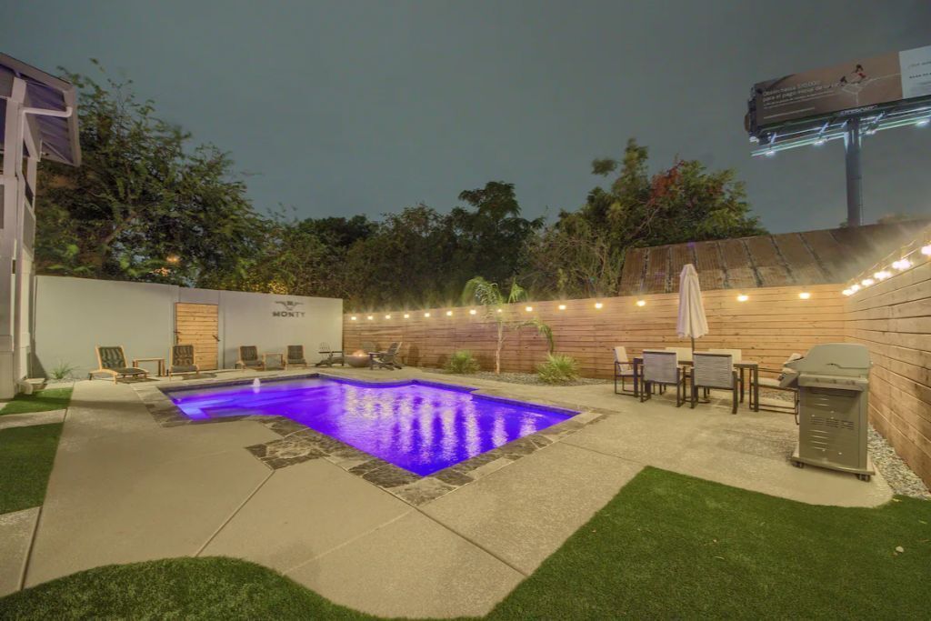 Ein Garten mit Schwimmbad, Gartenmöbeln und Lichterketten.