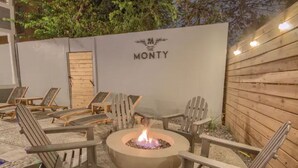 An outdoor seating area with Adirondack chairs and a central fire pit. - The Monty #2- Luxury,Downtown, near the River Walk (San Antonio)