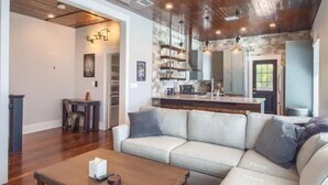 A modern living room with a wooden ceiling, a light-colored sofa, and a wooden coffee table. - The Monty #2- Luxury,Downtown, near the River Walk (San Antonio)