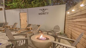 Een terras met Adirondack stoelen en een vuurkuil in het midden.