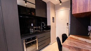 A modern kitchen with dark cabinetry, stainless steel appliances, and a marble countertop. - Studio de Luxo de Alta Qualidade (Bela Vista São Paulo)