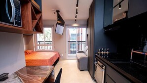 A compact kitchen with a built-in oven, a microwave, and a black countertop. - Studio de Luxo de Alta Qualidade (Bela Vista São Paulo)