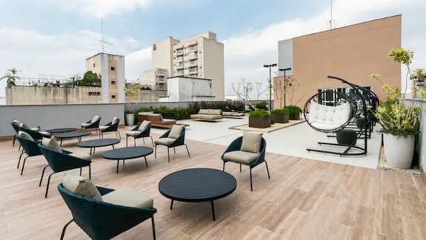 A rooftop terrace with round tables and chairs, a drum set, and potted plants. - Studio de Luxo de Alta Qualidade (Bela Vista São Paulo)