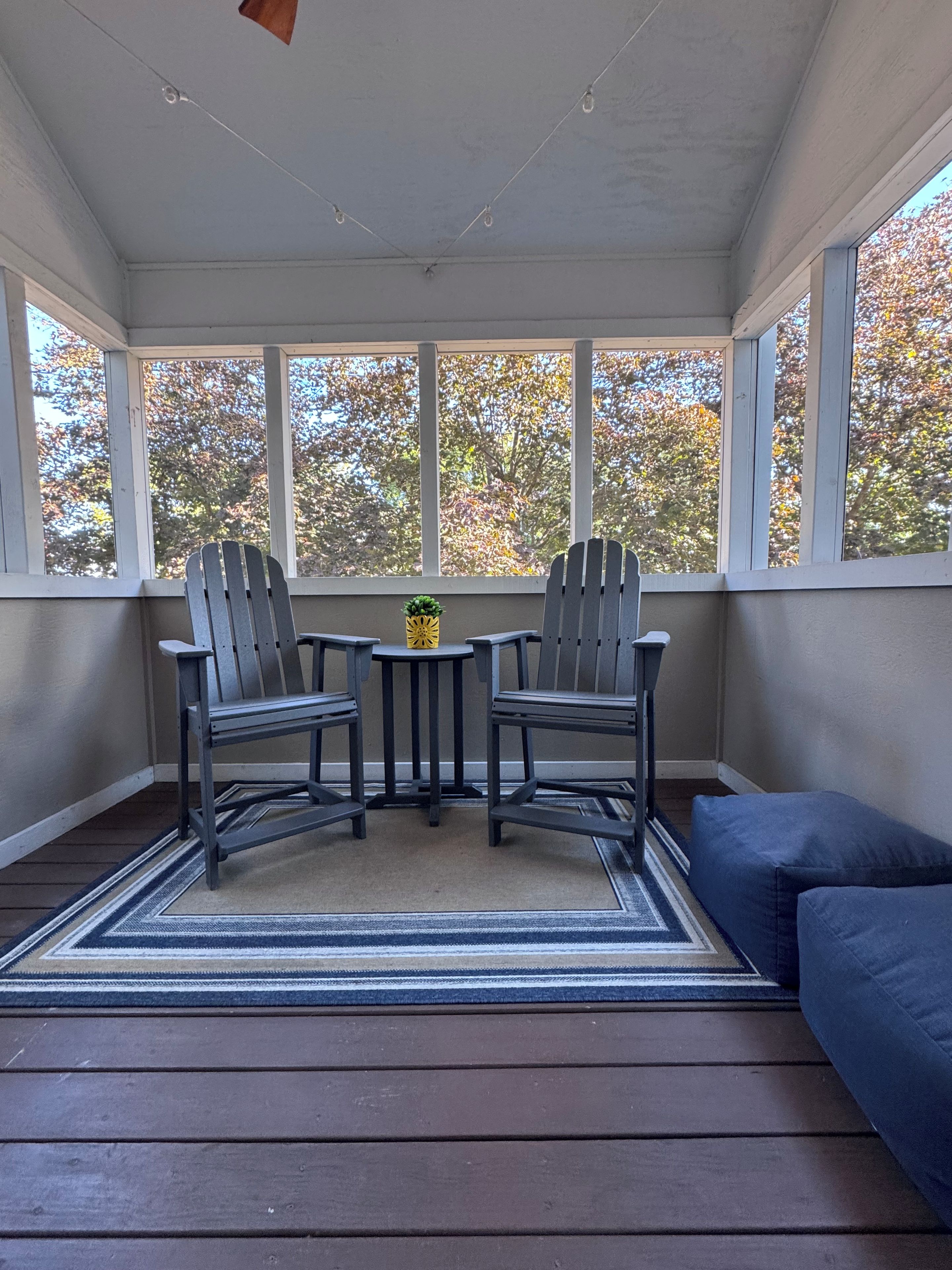 A covered patio with two Adirondack chairs, a small table, and a blue sofa.