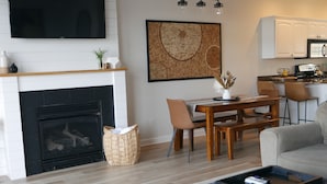 Ein modernes Wohnzimmer mit Kamin, Essbereich und einer Küche im Hintergrund.