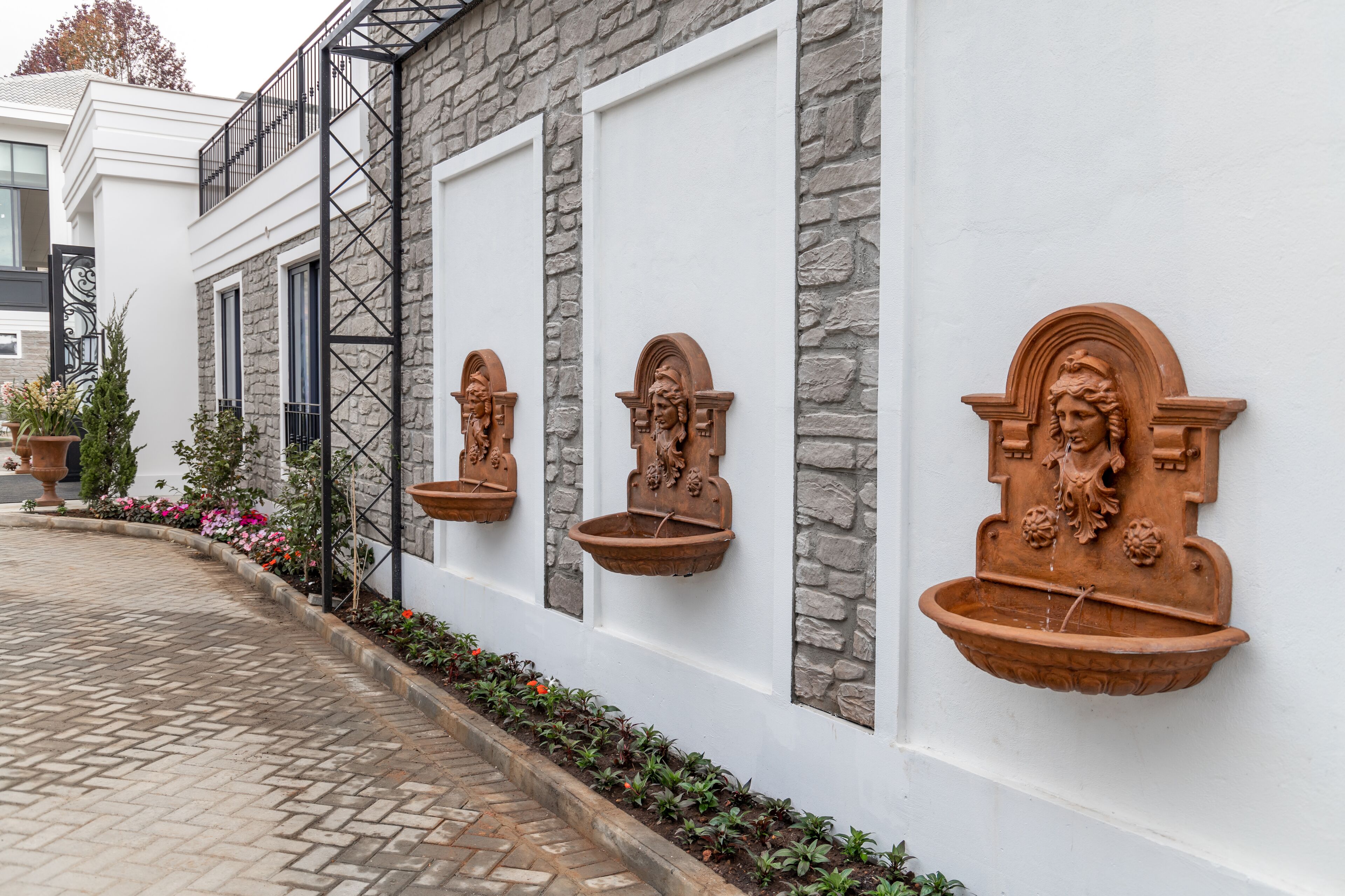 Un edificio con fachada de piedra, paredes blancas y macetas de terracota montadas en la pared con figuras decorativas.
