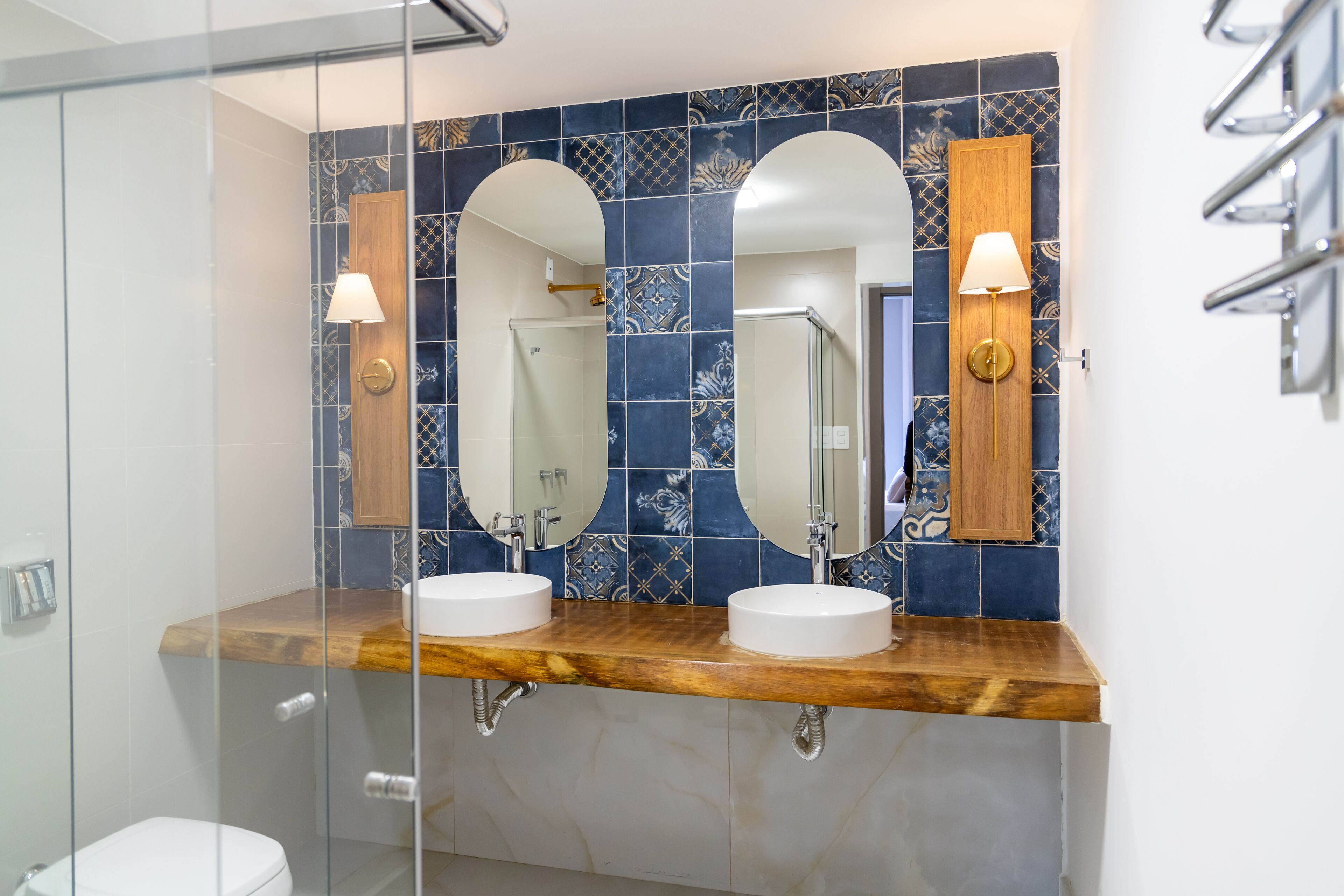 A bathroom with two sinks, a glass shower enclosure, and a wooden vanity.