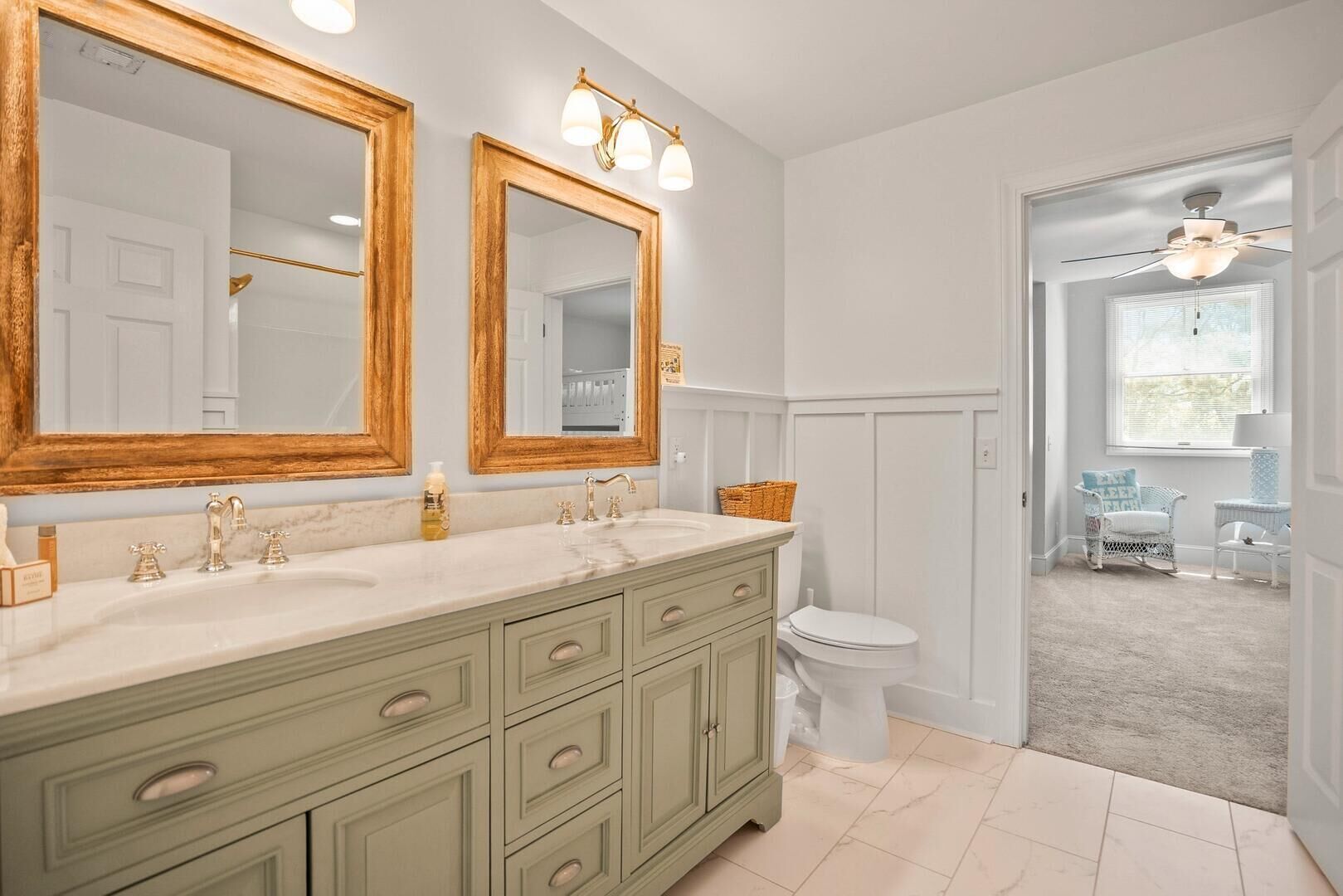 A bathroom with a vanity, two mirrors, a toilet, and a view into a dining area.
