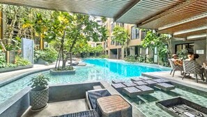 A swimming pool with tiled steps, surrounded by greenery and outdoor seating. - The Base - New Studio Great Location, Shared Pool (Wichit)