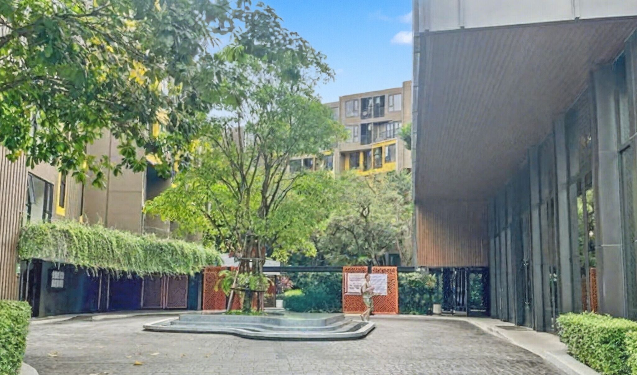 A courtyard with a water feature, surrounded by buildings with modern architecture and greenery.