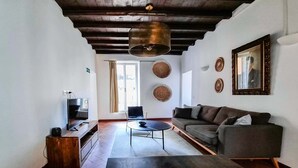 A modern living room with a wooden ceiling, a sofa, a coffee table, and a TV. - Cozy Flat near Castel S. Angelo (Rome)
