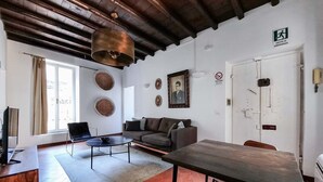 A spacious living room with a wooden ceiling, a sofa, a coffee table, and a dining table. - Cozy Flat near Castel S. Angelo (Rome)