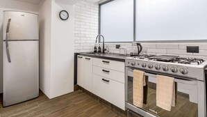 Een moderne keuken met een roestvrijstalen koelkast, een gasfornuis en witte keukenkastjes.