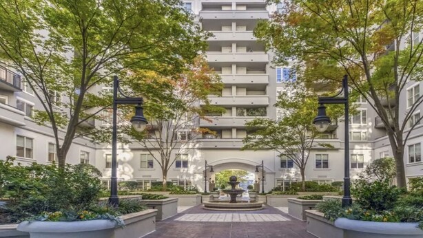 Un patio central con una fuente, rodeado de árboles y edificios modernos.