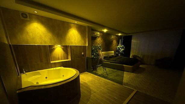 A modern bathroom with a freestanding bathtub, a large mirror, and a wooden floor. - ÇANKAYA SUIT HOTEL (Ankara)