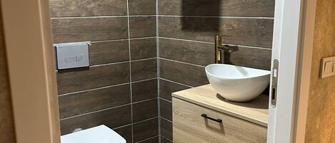Un baño moderno con inodoro, lavabo y tocador de madera.