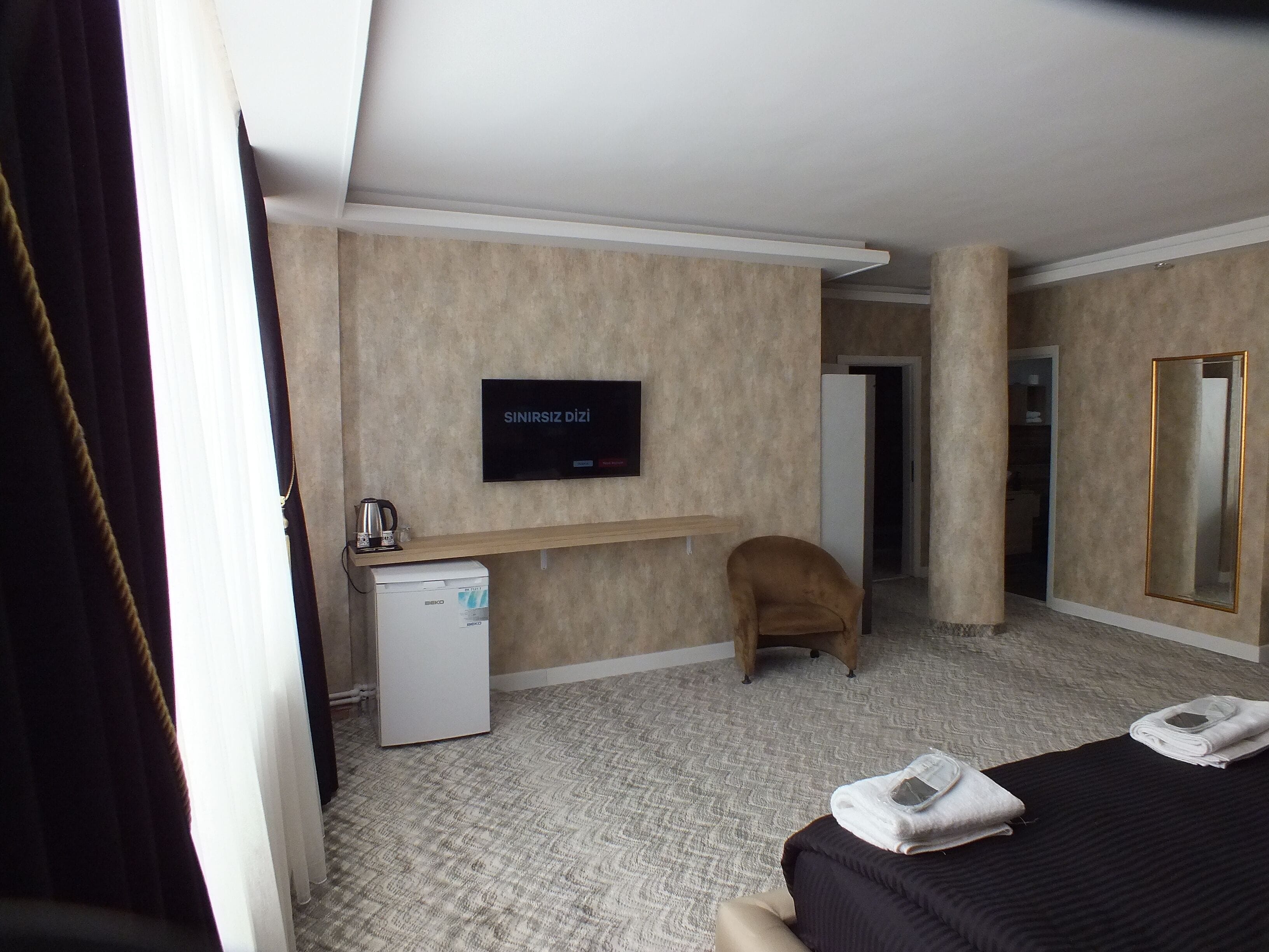 Une chambre d’hôtel équipée d’un lit, d’un bureau avec une machine à café, d’une télévision et d’un miroir.