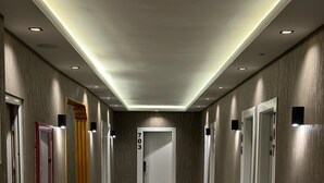 A hallway with carpeted floors, wooden walls, and doors numbered 703, 706, and 707. - ÇANKAYA SUIT HOTEL (Ankara)