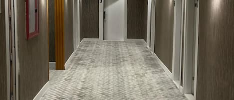 Un pasillo con pisos alfombrados, paredes de madera y puertas numeradas 703, 706 y 707.