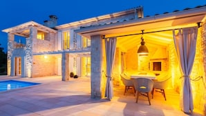 En lyxig villa med pool, en utomhusplats med sittmöbler och en täckt uteplats.