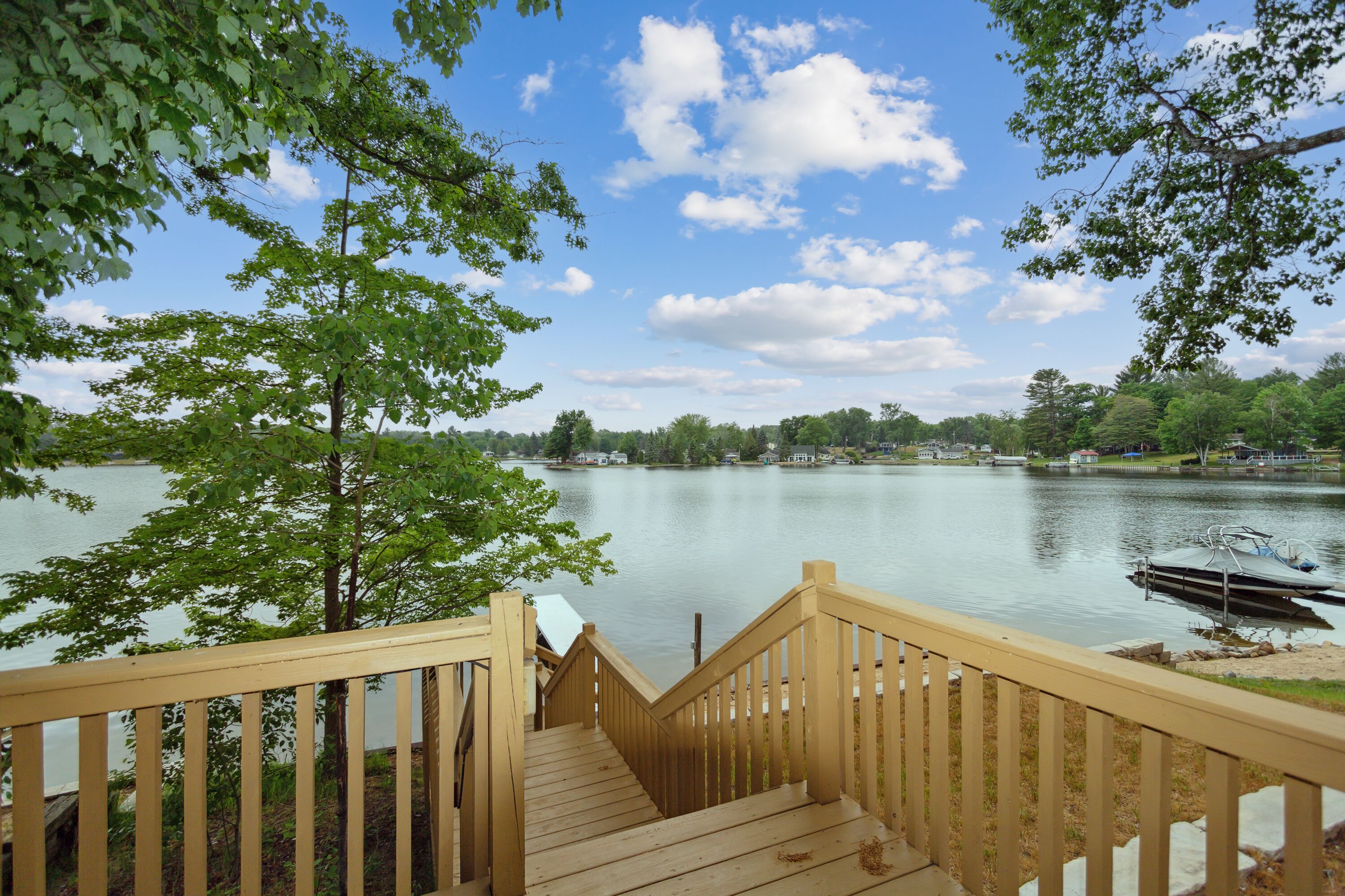A wooden deck leading to a lake with a boat docked on the right.