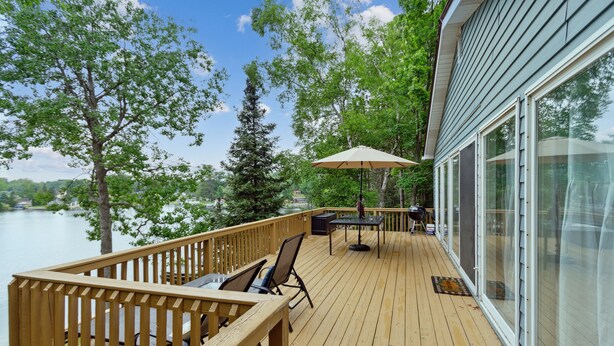 A wooden deck with outdoor furniture, a table, and an umbrella.