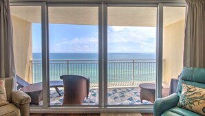 A balcony with a view of the ocean, furnished with a chair and a small table.