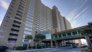 A high-rise hotel with a clear entrance, multiple balconies, and a modern glass structure.