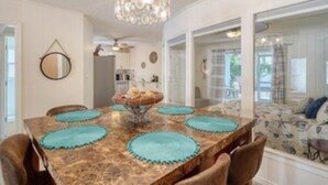 Un coin repas avec une table en marbre, des sets de table turquoise et un lustre.