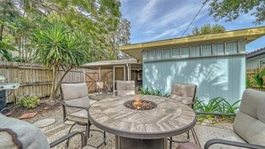 Une terrasse avec une table ronde et quatre chaises, un foyer extérieur et une clôture en bois.