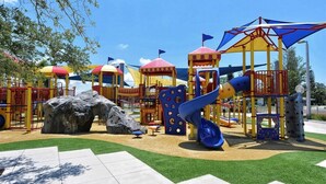 Une aire de jeux avec des structures d’escalade, des toboggans et un élément décoratif en forme de rocher.