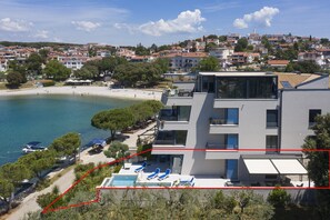 A modern building with a pool, beach view, and multiple balconies.