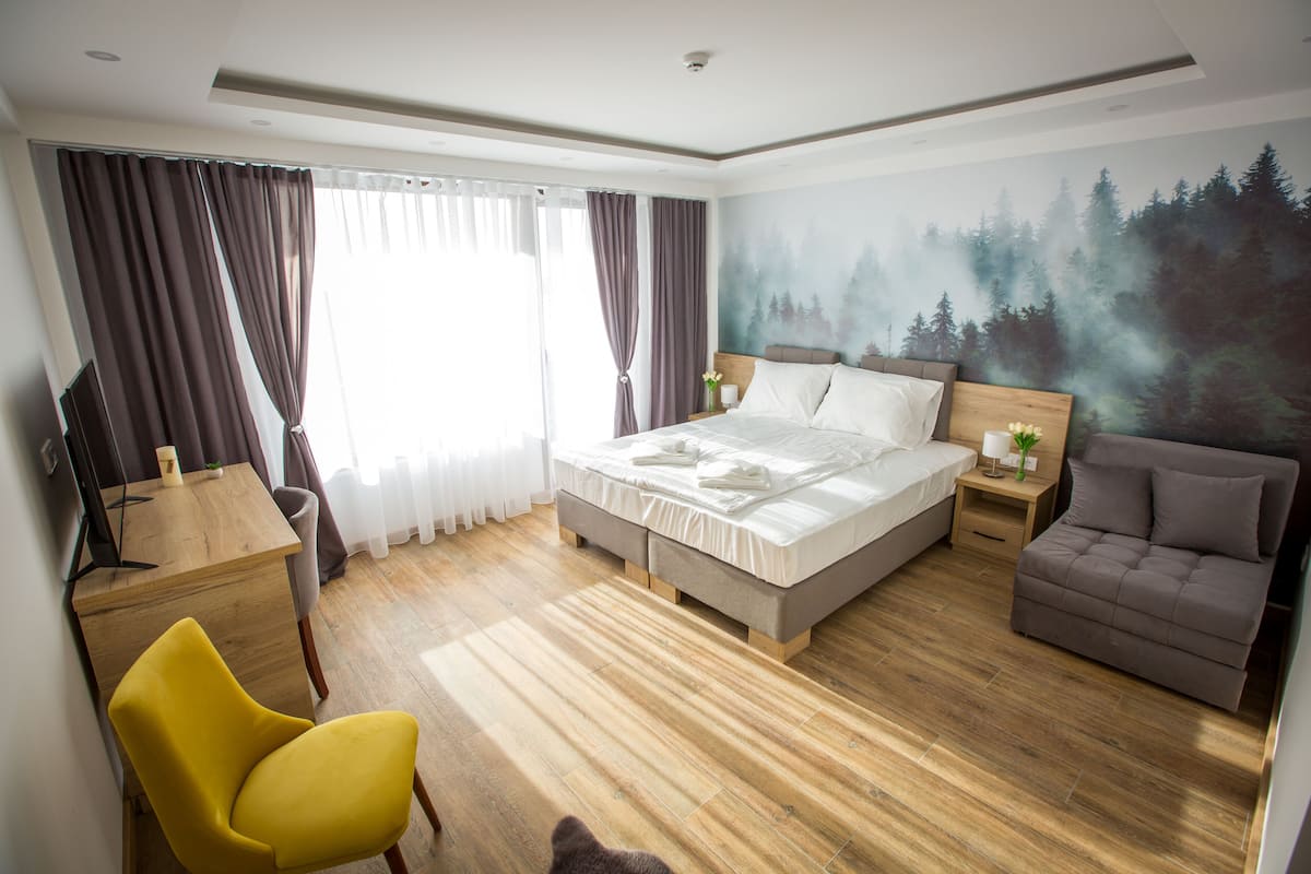 Hotellihuone, jossa on sänky, sohva, työpöytä ja tuoli.