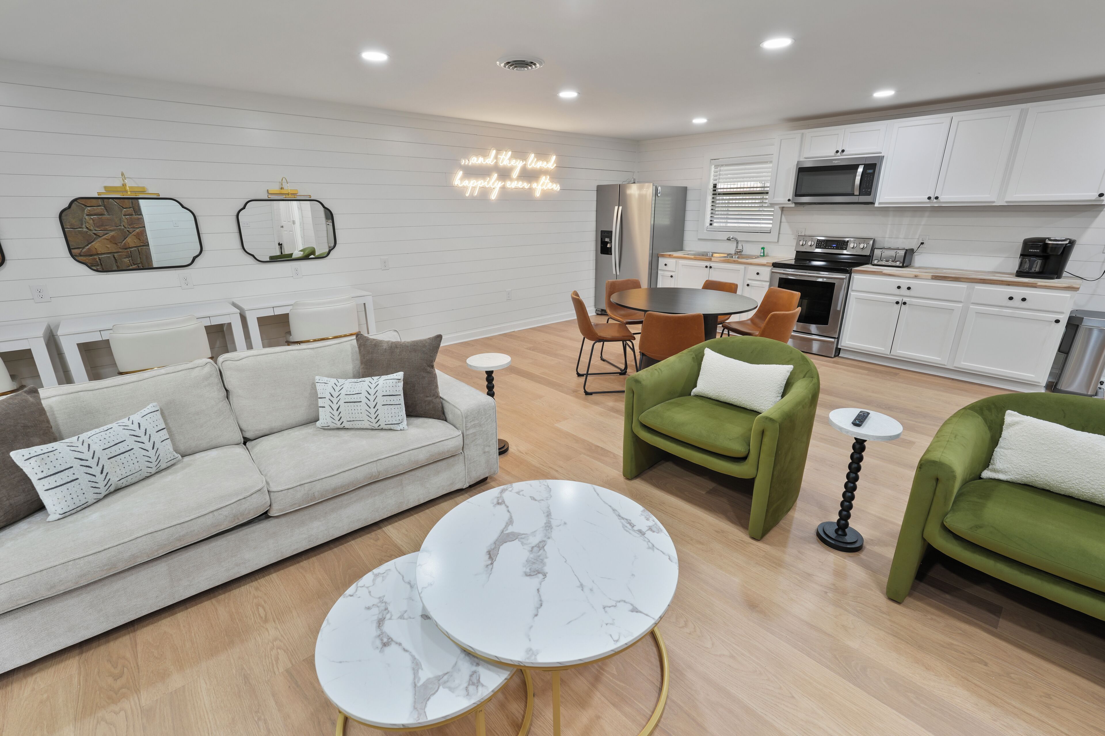 A modern living room with a sofa, green armchairs, and a marble coffee table.