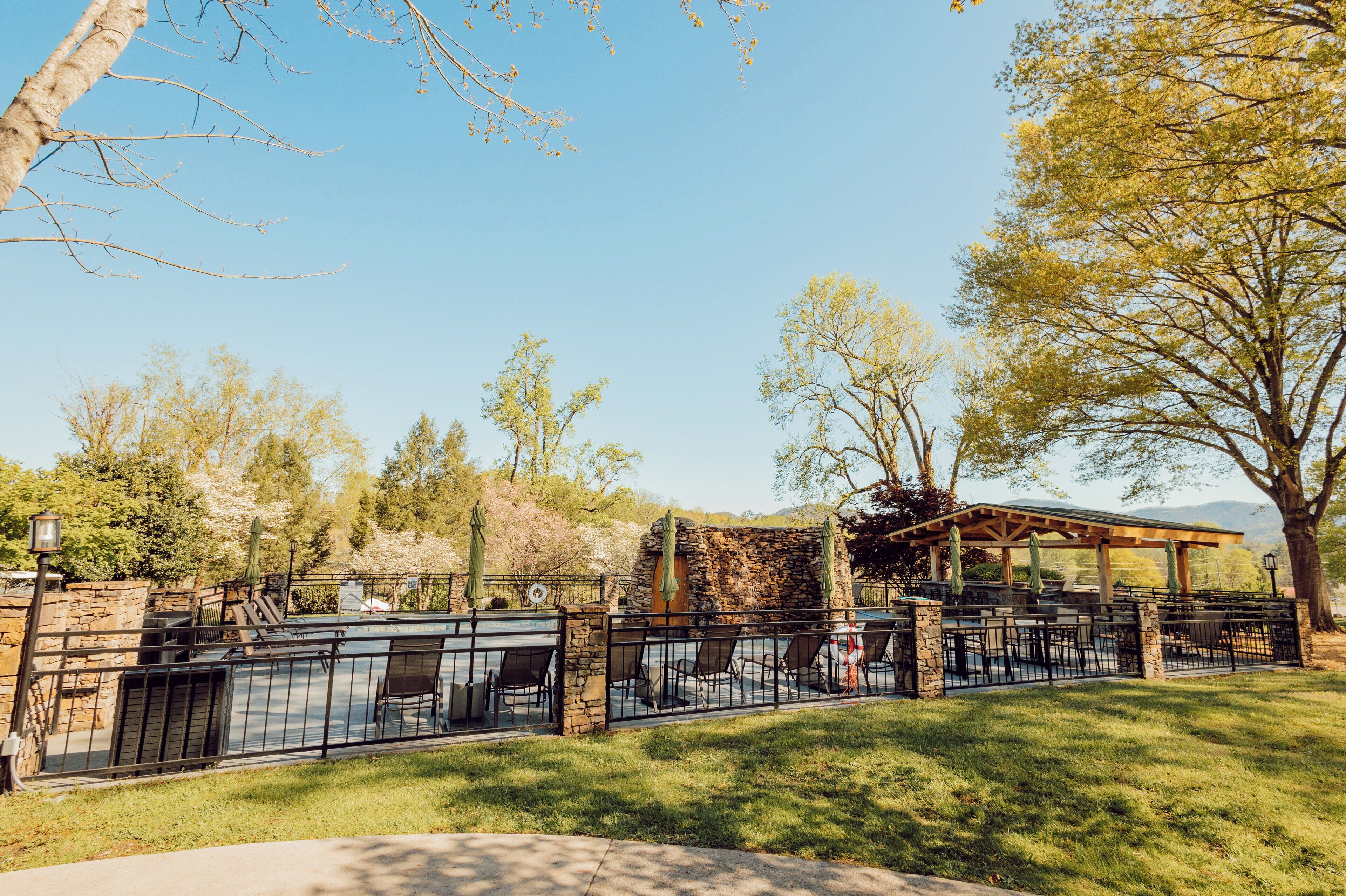 An outdoor patio area with stone walls, a pergola, and tables and chairs.