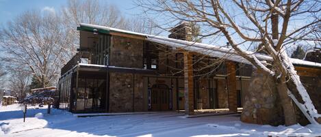 A stone building with a balcony and a snow-covered landscape.