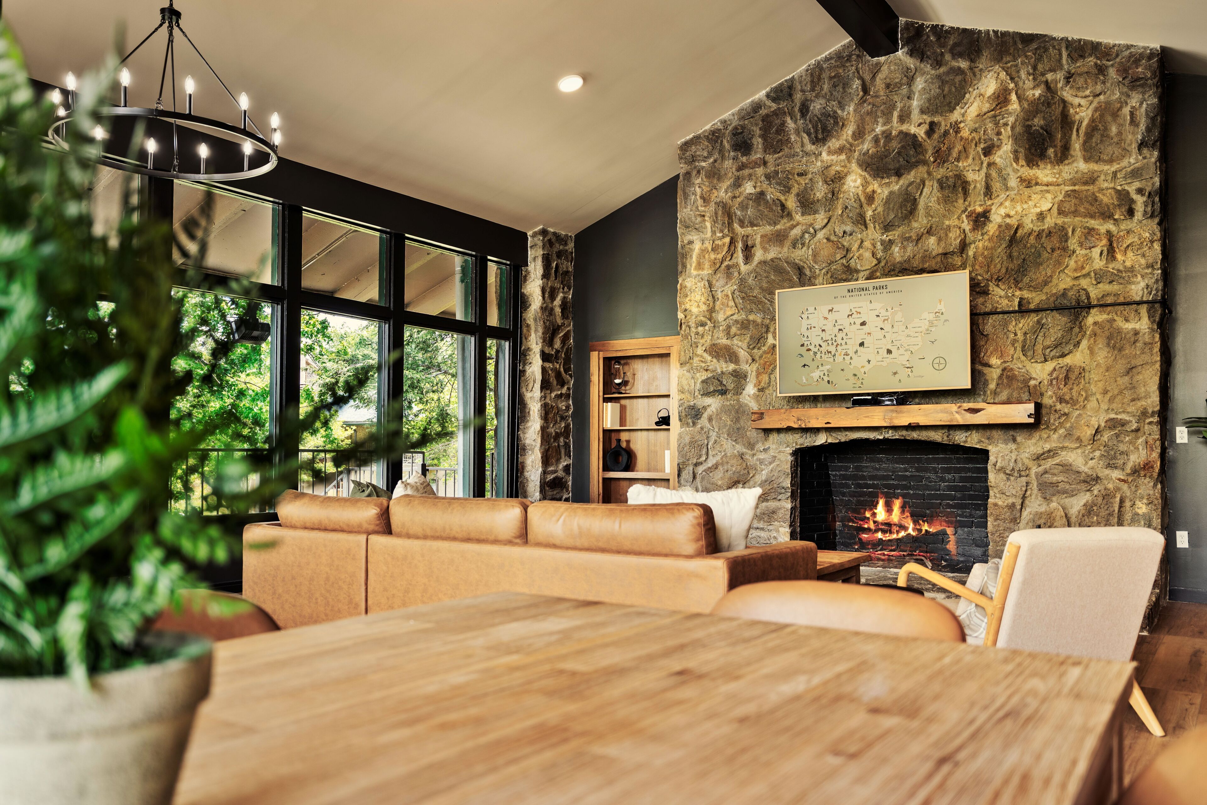 A modern living room with a stone wall, a fireplace, leather sofas, and a dining table.