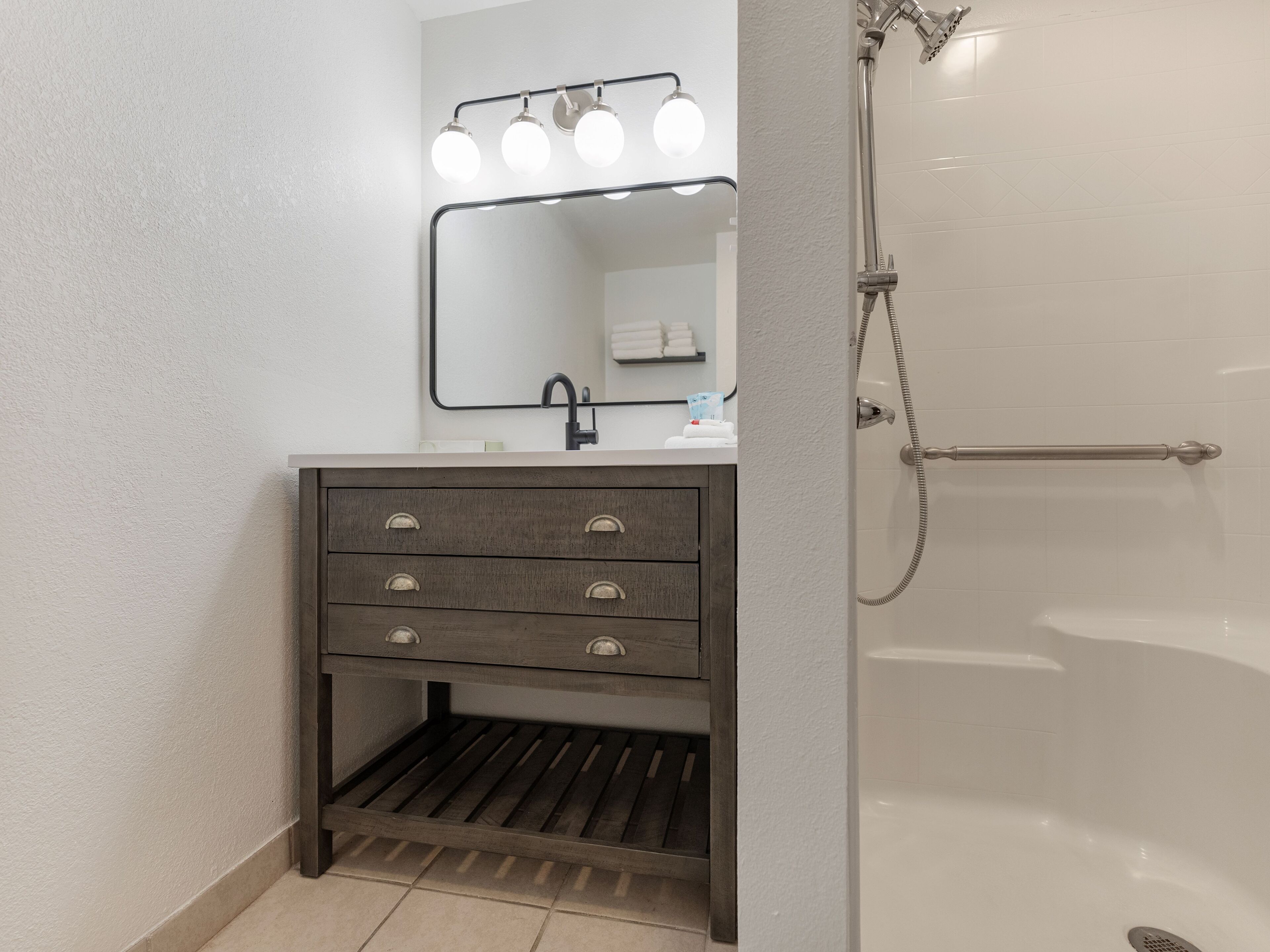 Een badkamer met een wastafel, spiegel en douche.