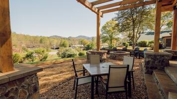 An outdoor patio with stone walls, a pergola, and a view of a mountainous landscape.
