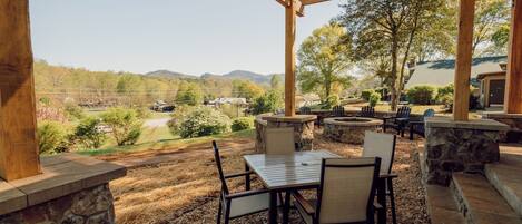 An outdoor patio with stone walls, a pergola, and a view of a mountainous landscape.