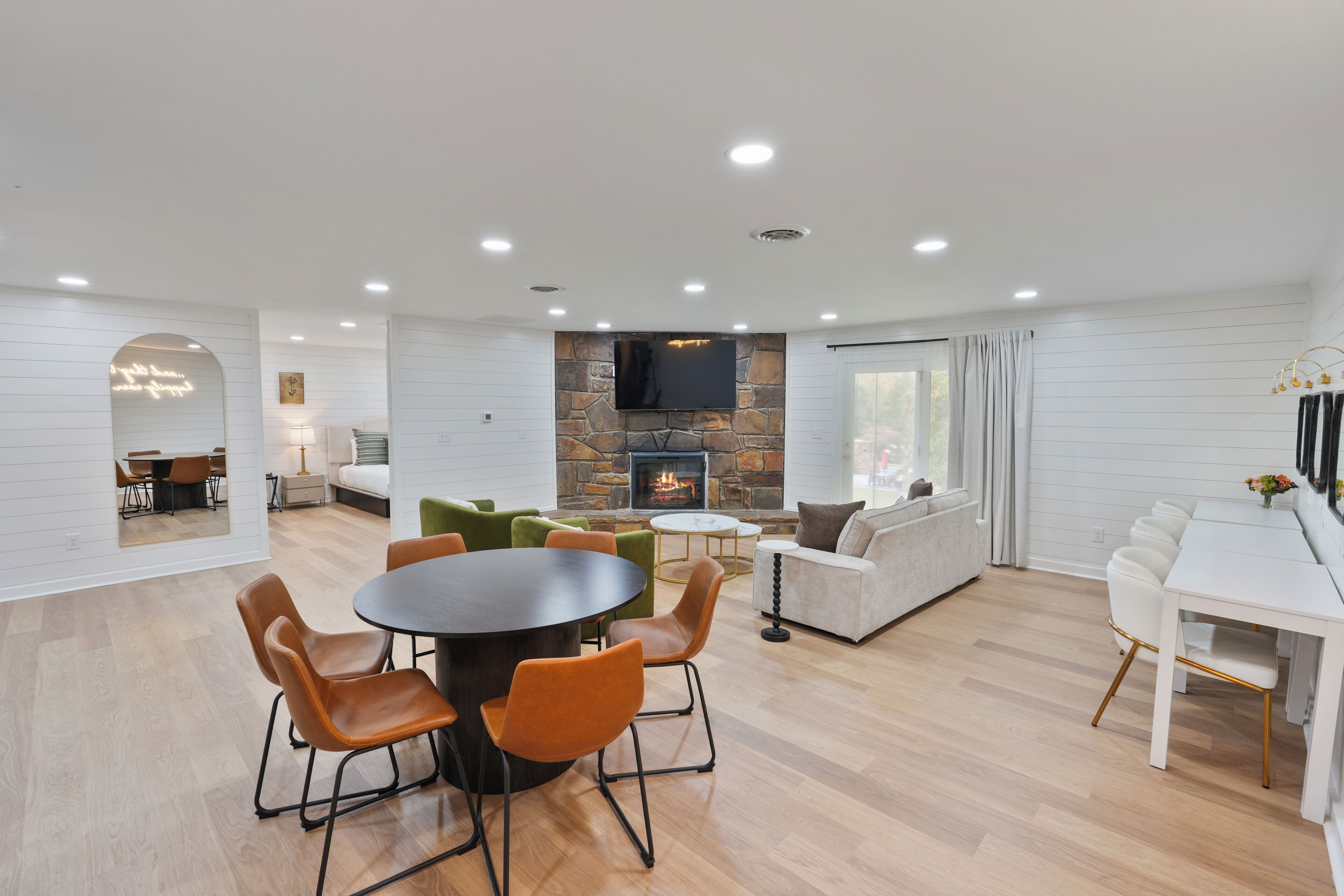 Amplia sala de estar con chimenea, comedor con una mesa redonda y sillas, y zona de estar con sofás y sillones.