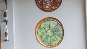 Une pièce dotée d’un plafond en bois, d’un élément décoratif en métal fixé au mur et de trois fenêtres rondes encadrées de bois.