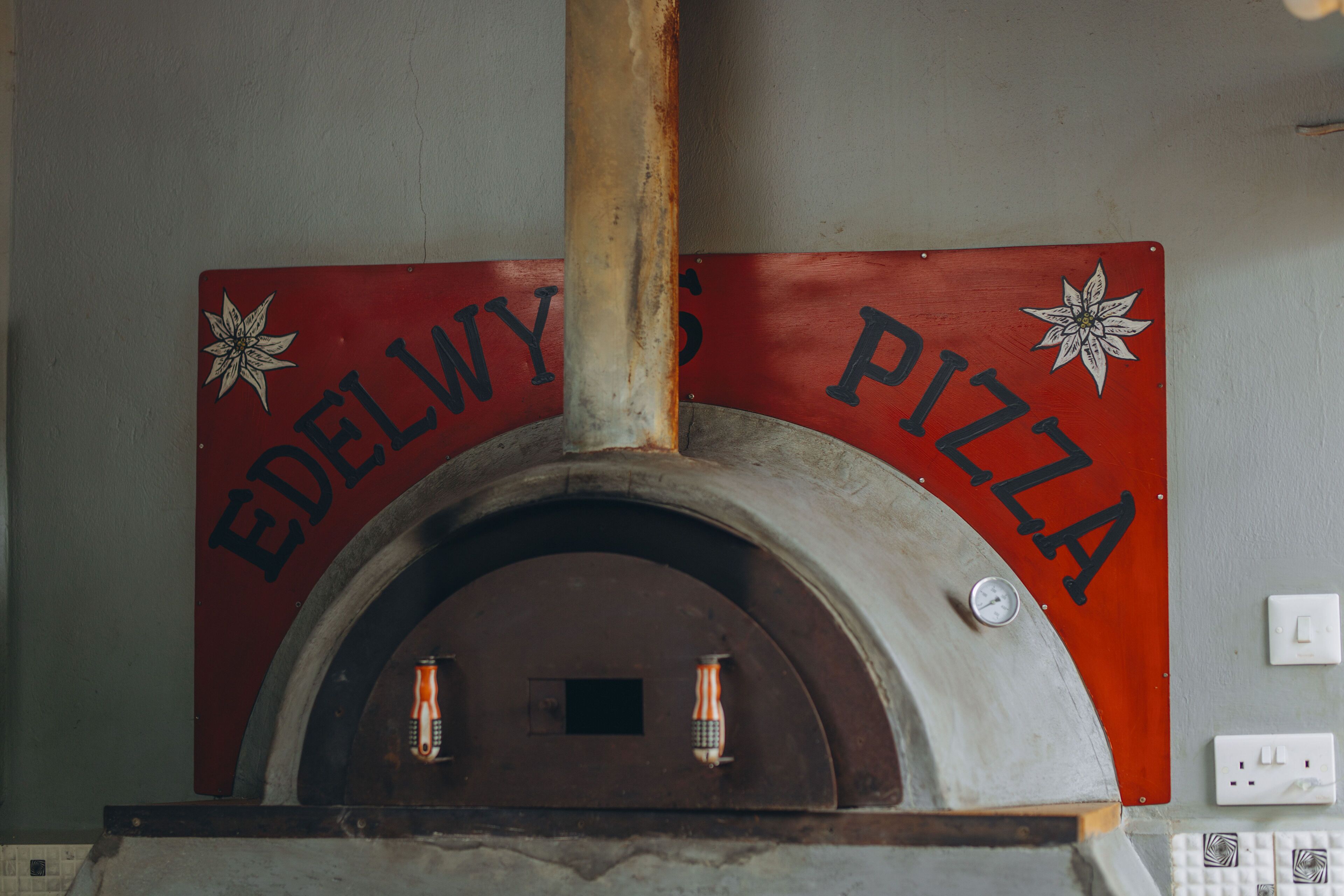 A brick oven with a sign above it reading "Edelwy's Pizza".