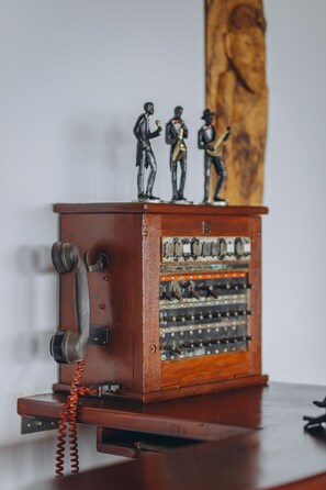 A vintage telephone with three figurines on top and a wooden cabinet. - Edelwyss-Inn (Morogoro)