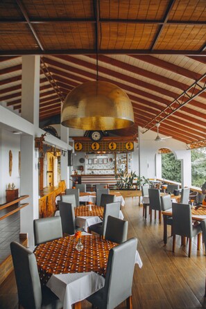 A restaurant with wooden tables and chairs, a bar area, and a large hanging light fixture. - Edelwyss-Inn (Morogoro)