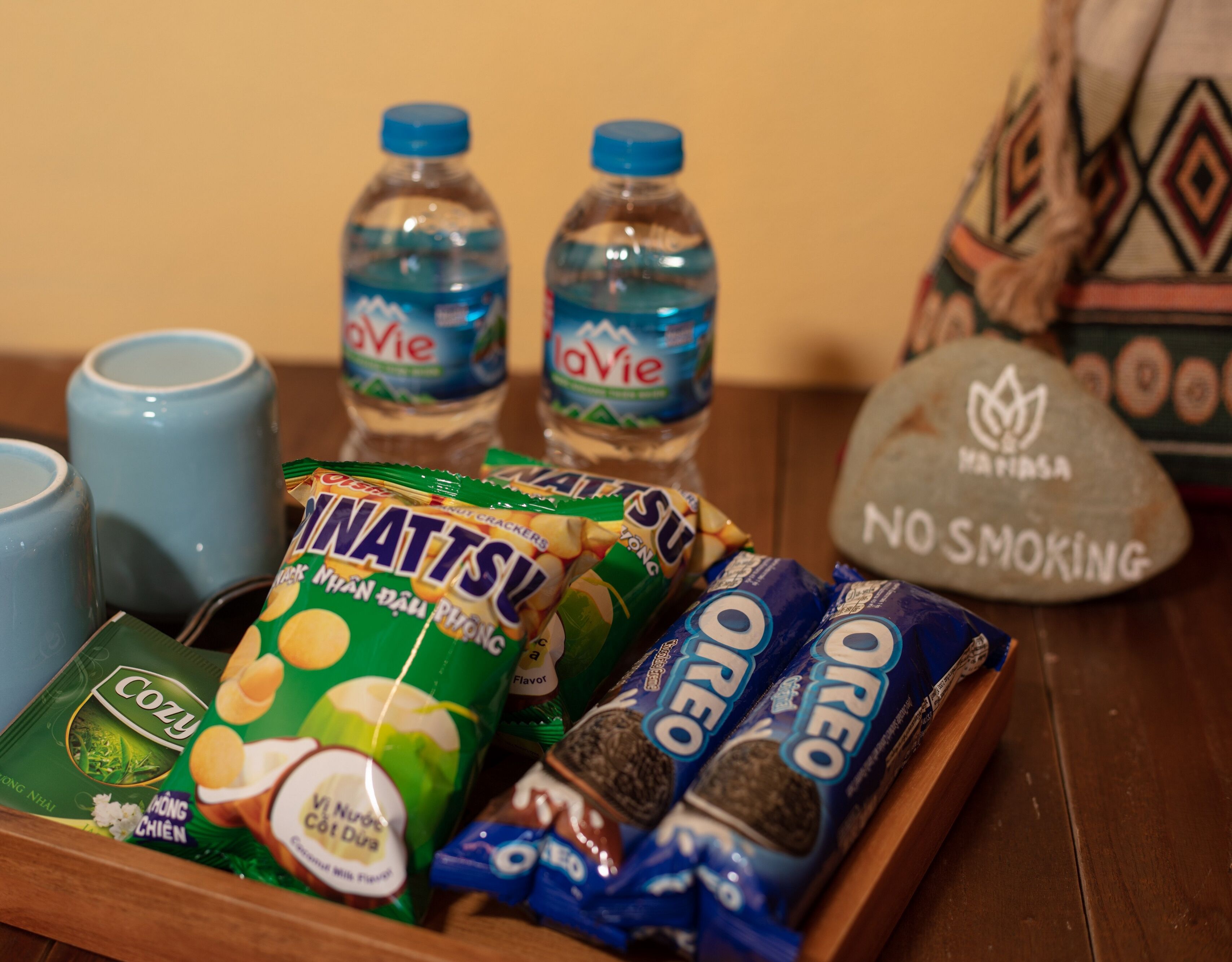 Una bandeja con aperitivos, botellas de agua y un cartel de 'No Smoking'.