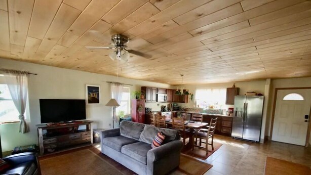 Ein geräumiger Wohnbereich mit grauem Sofa, Holzboden und einer Küche im Hintergrund.